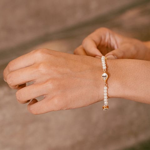 Woman wearing a delicate pearl beaded bracelet with metallic accents on her wrist
