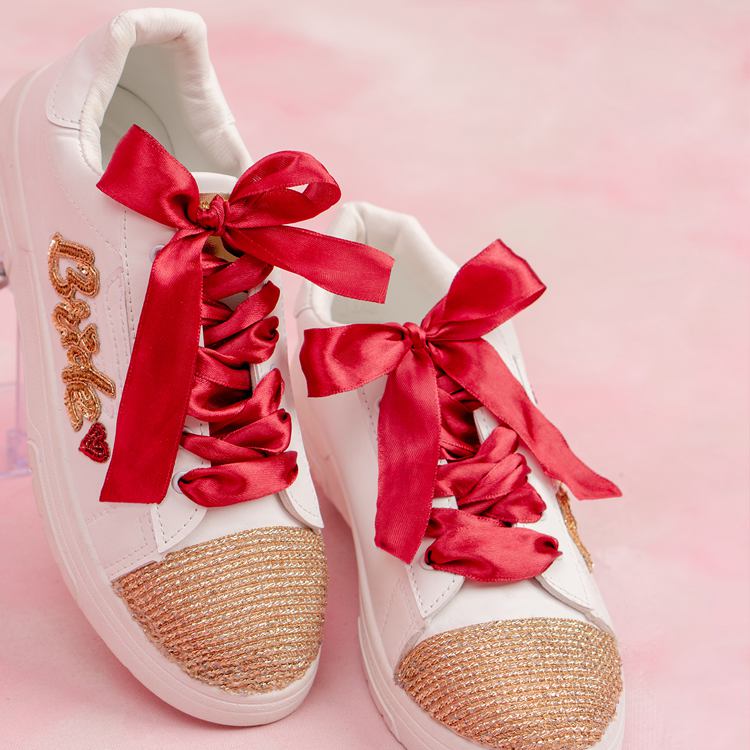 White women's sneakers with gold sequin toes, red satin laces, and bridal embroidery.